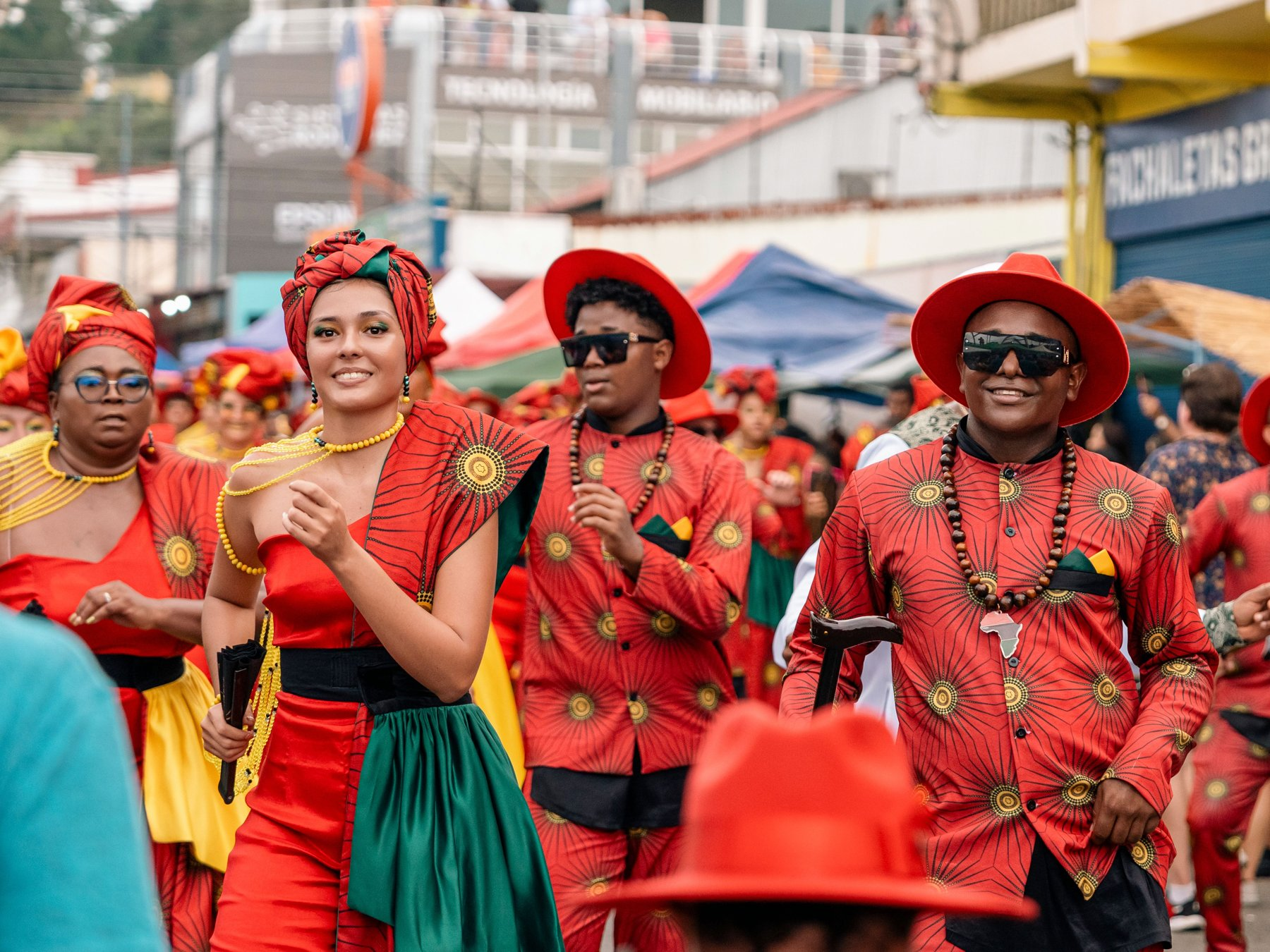 Comparsa vestida de rojo, verde y dorado marchando en el desfile Wolaba de Limon