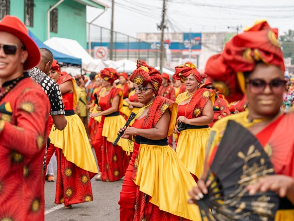 Grupo de baile con trajes rojos y amarillos y abanicos en el desfile Wolaba de Puerto Viejo