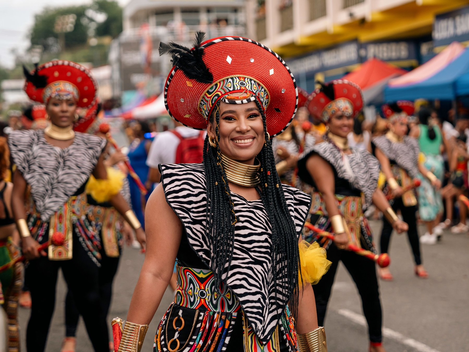 Mujer con un tocado rojo de plumas y traje festivo en el desfile Wolaba de Puerto Viejo