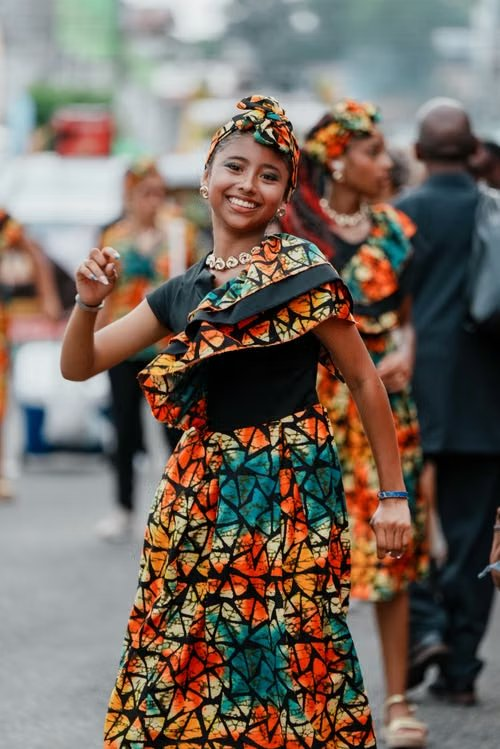 Nina sonriendo y bailando con un vestido de tela africana en el desfile Wolaba