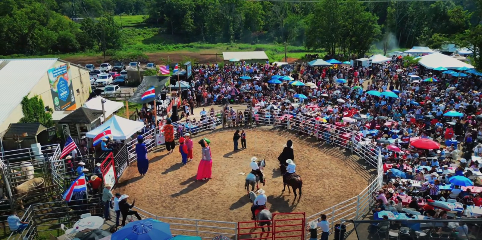 El redondel de La Finca lleno de gente, con las mascaradas y caballos en la arena durante Zapote USA
