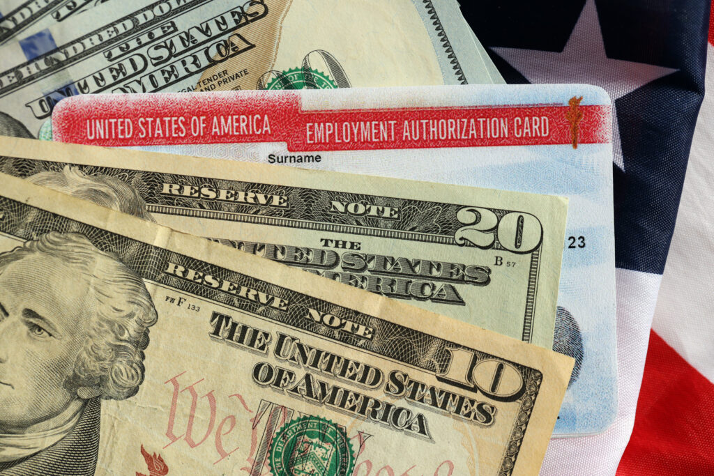 Tarjeta de permiso de trabajo de Estados Unidos (Employment Authorization Card) de muestra, con billetes de dólar sobre la bandera estadounidense