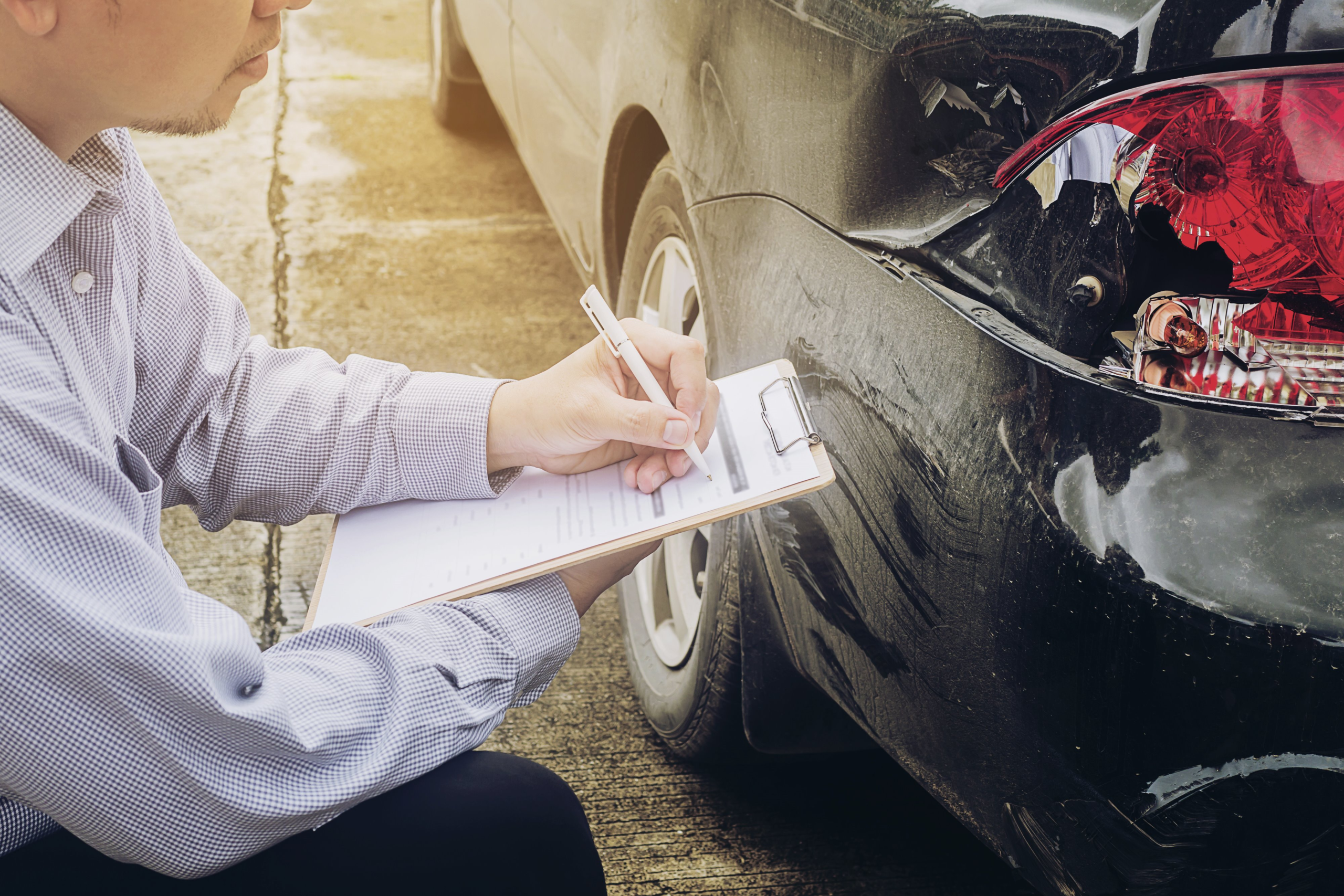 Agente de seguros revisando un carro después de un choque